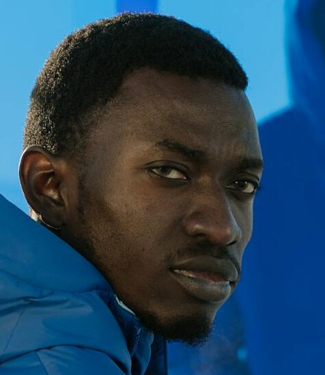 Stylish portrait of a man in a blue winter jacket, featuring artistic reflections and a snowy backdrop.